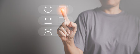Customer service and Satisfaction concept, Business person are touching the virtual screen on happy Smiley face icon to give satisfaction in service. rating very impressed. customer service feedback.の写真素材