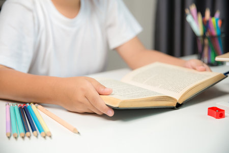 Boy person sitting study indoor at home, Male kid student online learning and doing homework on desk, young child reading and writing a book on table. concept of education, technology cyberspaceの写真素材