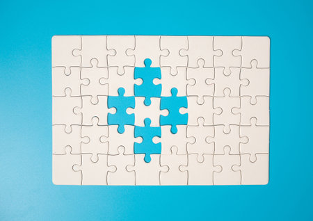 White part of jigsaw puzzle pieces on blue background. concepts of problem solving, business success, teamwork, Team playing jigsaw game incomplete, Texture photo with copy space for textの写真素材