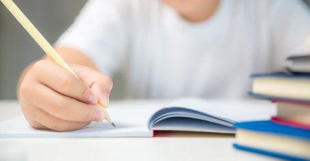 Boy person sitting study indoor at home, Male kid student online learning and doing homework on desk, young child reading and writing a book on table. concept of education, technology cyberspaceの写真素材