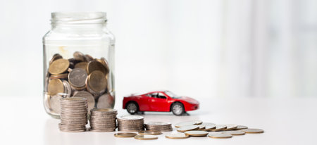 Car toy vehicle with stack coin money on background. Planning to manage transportation finance costs. Concept of car insurance business, saving buy - sale with tax and loan for new car.の写真素材