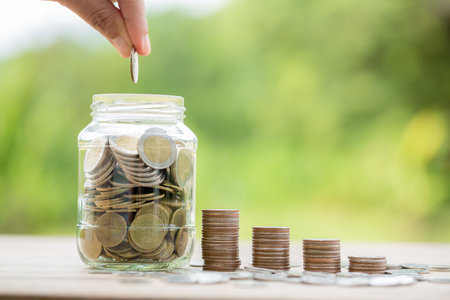 Female hand holding or putting money coin for saving. management cash, insurance asset and wealth, tax accounting budget, growth loan financial, economic, savings for business investments concept.の写真素材