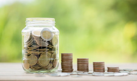 Savings for business investments concept. Money coin stacking on wood desk in green background. management cash, insurance asset and wealth, tax accounting budget, growth loan financial, economic.の写真素材