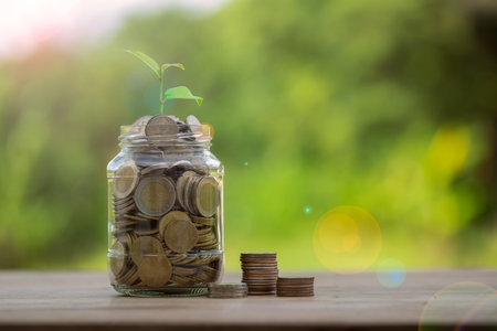 Money coin stack growing graph with glass jar saving concept. business finance and saving money investment, plant growing up on coin. Balance savings and investment. save retirement for interest ideaの写真素材