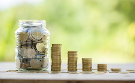 Savings for business investments concept. Money coin stacking on wood desk in green background. management cash, insurance asset and wealth, tax accounting budget, growth loan financial, economic.の写真素材