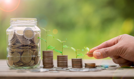 Hand putting money coin. Money coin stack growing graph with piggy bank saving concept. business finance and saving money investment, plant growing up on coin. Balance savings and investment.の写真素材
