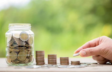 Female hand holding or putting money coin for saving. management cash, insurance asset and wealth, tax accounting budget, growth loan financial, economic, savings for business investments concept.の写真素材