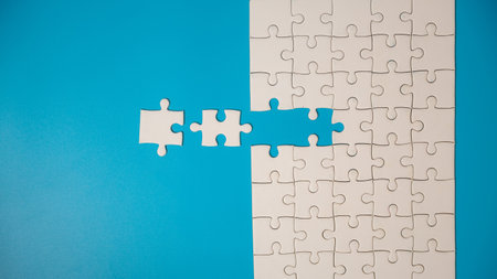 White part of jigsaw puzzle pieces on blue background. concepts of problem solving, business success, teamwork, Team playing jigsaw game incomplete, Texture photo with copy space for textの写真素材
