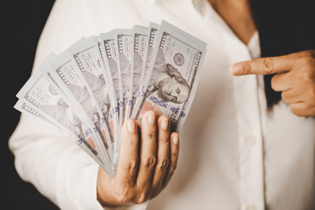 Banknote of 100 dollar bills in hands of rich woman person. Success business female holding cash money for investment. concept of saving finance, exchange bank, american currency, salary paymentの写真素材