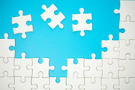 White part of jigsaw puzzle pieces on blue background. concepts of problem solving, business success, teamwork, Team playing jigsaw game incomplete, Texture photo with copy space for textの写真素材