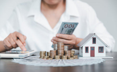Saving investment home with loan finance money business concept. Investment banking finance for residential real estate business. Stack coins with model house for investment loans.Cash for taxes.の写真素材