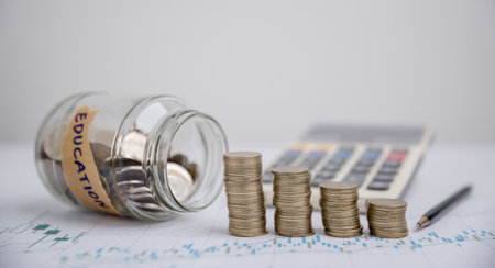 Concept to saving money income for study, Calculating student finance costs and investment budget loan. close-up education object with stack money coin-cash dollar and glass jar on background.の写真素材