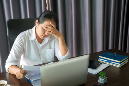 Stress business woman person from hard work, depression in office. Tired and anxious employee female with unhappy at problem job. young businesswoman sitting sad front of laptop computer on desk.の写真素材