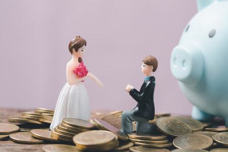 Save money for wedding and planning wedding concept. Sustainable financial goal for family life or married life. Miniature wedding on rows of rising coins, depicts savings or growth for new family.の写真素材