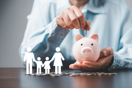 Businesswoman take a position to protect on the piggybank and paper family in hand, donation, saving, charity, family finance plan concept, fundraising, superannuation, financial crisis conceptの写真素材