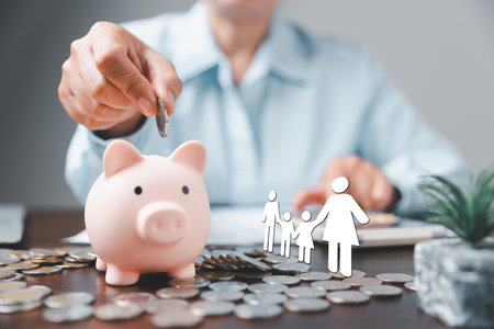 Businesswoman take a position to protect on the piggybank and paper family in hand, donation, saving, charity, family finance plan concept, fundraising, superannuation, financial crisis conceptの写真素材