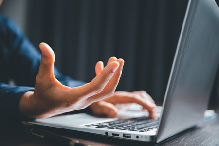 Closeup of businesswoman typing on laptop computer while sitting on table in office for design work, insert icons or business technology symbols. selective focus on hand. female online working on deskの写真素材