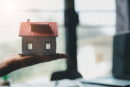 Business woman holding home miniature in office bureau. insurance protective hand over house for protection and care, Concept of home and real estate Property insurance.の写真素材