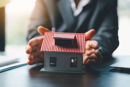 Female hands saving small house with a roof. insurance protective hand over house for protection and care, Concept of home and real estate Property insurance. close up of hands sheltering modern houseの写真素材