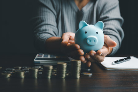 Business woman hand holding piggy bank on wood table background, saving money wealth and financial concept, finance, investment, Financial planning.Financial planning deposit for retirement.の写真素材