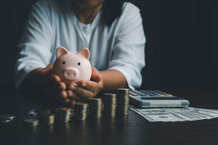 Business woman hand holding piggy bank on wood table background, saving money wealth and financial concept, finance, investment, Financial planning.Financial planning deposit for retirement.の写真素材