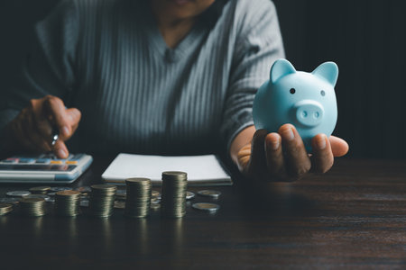 Business woman hand holding piggy bank on wood table background, saving money wealth and financial concept, finance, investment, Financial planning.Financial planning deposit for retirement.の写真素材