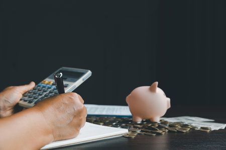 Business woman hand take note with piggy bank on wood table background, saving money wealth and financial concept, finance, investment, Financial planning. Financial planning deposit for retirement.の写真素材