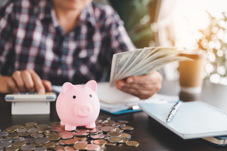 Pink piggy bank with business woman hand calculating expenses, saving money wealth and financial concept, finance, investment, Financial planning. Financial planning deposit for retirement.の写真素材