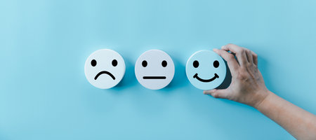 Woman hand holding happy face smile face icon on round blue object. Customer experience and service with satisfaction concept. positive thinking, mental health assessment, world mental health day.の写真素材