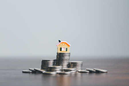 Coins stack with mini house on wooden table, home loan, Save money concept, Property investment, house loan, reverse mortgage, gold coins money stack growth, saving money coins stack future for home.の写真素材