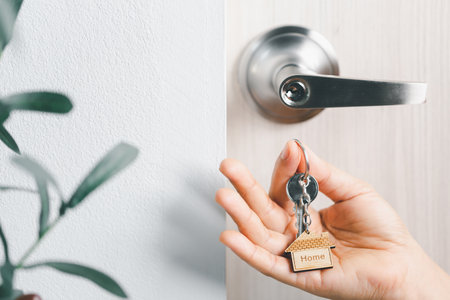 close up key on the door with morning light, personal loan concept. House model and key in house...