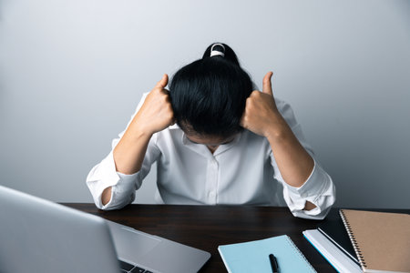 A business office worker is an asian woman is sitting in front of the laptop computer. A...