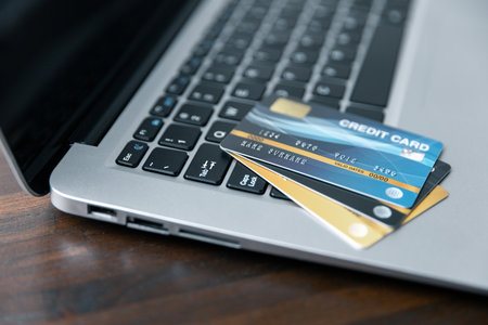 Modern Laptop on Business Work Desk with Credit Card - Technology and Finance Concept. Professional Business Workspace with Laptop, Keyboard, and Credit Card - Digital Economy.の写真素材