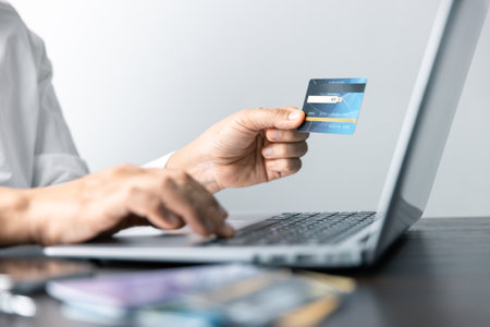 Focused businesswoman utilizing a credit card to manage transactions efficiently at a contemporary desk. Professional working highlighting modern finance, online shopping, digital technology.の写真素材