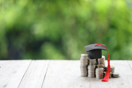 Knowledge and Success: Graduation Cap on Books Against a Beautiful Nature Background. Achievement Unlocked: Graduation Cap and Books Symbolize Education Savings and Academic Growth.の写真素材