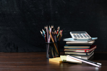 Back to school background with books on wooden table over chalkboardの写真素材