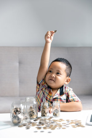 Preschooler child learning to calculate personal budget, manage finance, playing investment, accounting. Focused school kid saving money for purchase, putting cash in pink piggy bank at home.の写真素材