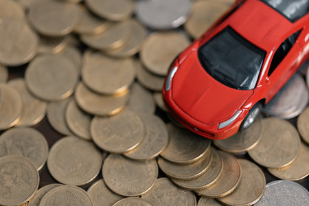 Miniature car model and Financial statement with coins. Finance and car loan, saving money for a car concepts. Car loan, money, banknote on agreement document or car insurance application form.の写真素材