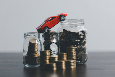 Miniature car model and Financial statement with coins. Finance and car loan, saving money for a car concepts. Car loan, money, banknote on agreement document or car insurance application form.の写真素材