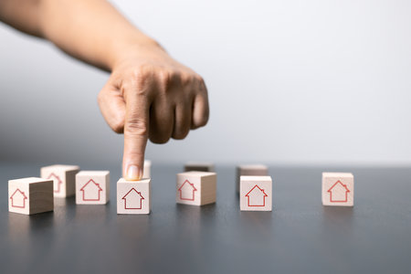 House and property investment and asset management concept. Interest rates, loan mortgage, house tax. Hand holding house icon on wooden block from stack with percent icon. Copy space for text.の写真素材