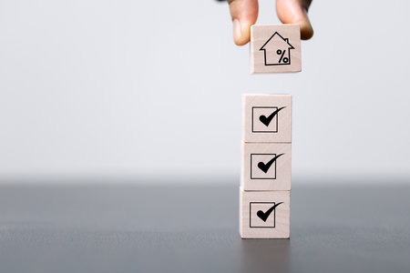 House and property investment and asset management concept. Interest rates, loan mortgage, house tax. Hand holding house icon on wooden block from stack with percent icon. Copy space for text.の写真素材