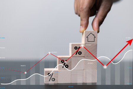 House and property investment and asset management concept. Interest rates, loan mortgage, house tax. Hand holding house icon on wooden block from stack with percent icon. Copy space for text.の写真素材