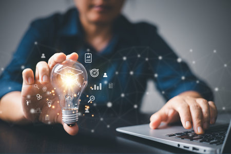 Hand holding light bulb showing graduation cap internet education creative with icon and study work...