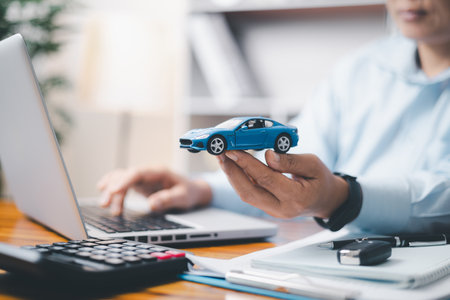 Toy Car In Front Of Businessman Calculating Loan. Saving money for car concept, trade car for cash concept, finance concept.の写真素材