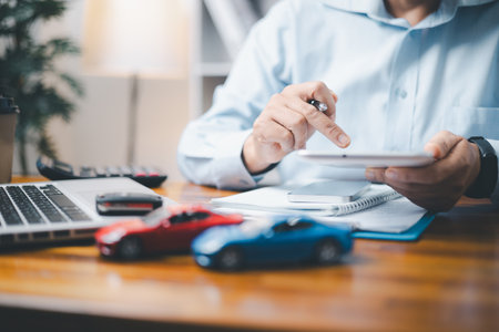 Toy Car In Front Of Businessman Calculating Loan. Saving money for car concept, trade car for cash concept, finance concept.の写真素材