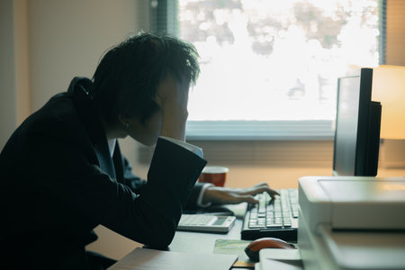 Stressed businessman, sleepy man working in his office, sat at his computer, feeling weight of his...