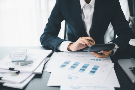 Business professional analyzing financial data and growth charts, reviewing investment reports and financial performance metrics on a desk.の写真素材