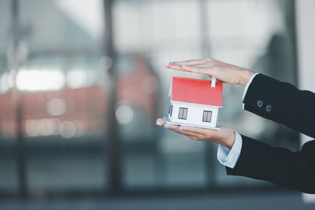 Woman hand hold key buy home model business concept involves sell financial management investment bank loan ownership income economy finance investments purchasing apartment blur background estateの写真素材