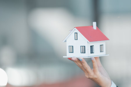 Woman hand hold key buy home model business concept involves sell financial management investment bank loan ownership income economy finance investments purchasing apartment blur background estateの写真素材