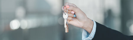 Woman hand hold key buy home model business concept involves sell financial management investment bank loan ownership income economy finance investments purchasing apartment blur background estateの写真素材